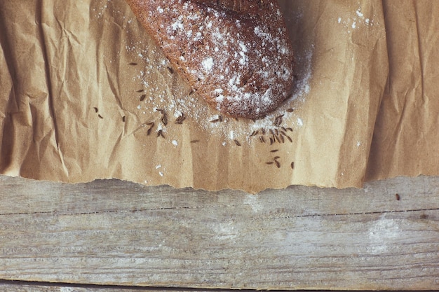 Pains de pain rustiques frais cuits au four dans des sacs en papier sur fond de bois foncé