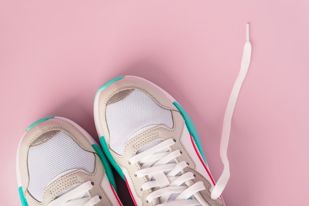 Une paire de baskets blanches sur un mur rose