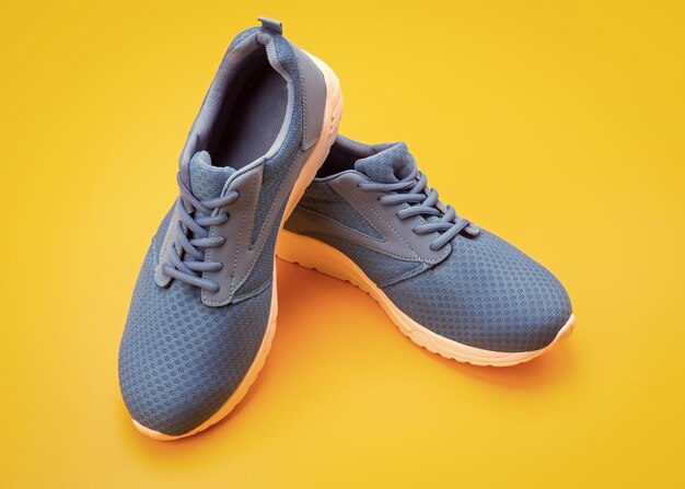 Paire de baskets bleues sportives sur fond jaune