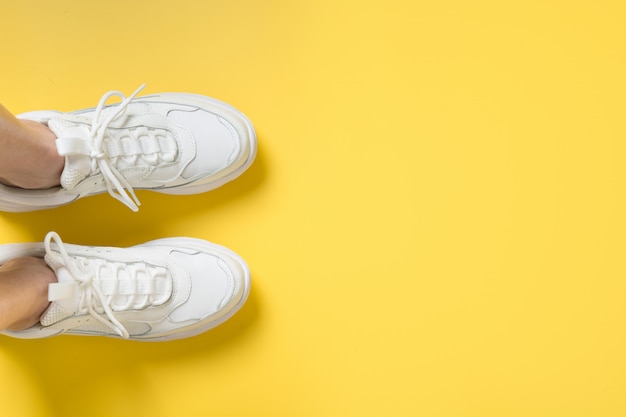 Paire De Baskets Femelles Blanches Sur Fond Jaune. Lay Plat, Vue De Dessus Minimale.