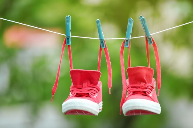 Paire de baskets rouges accrochées à une corde à linge à l'extérieur