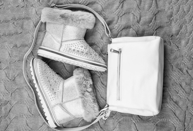 Photo une paire de bottes d'hiver à la mode et un sac en cuir sur fond tricoté