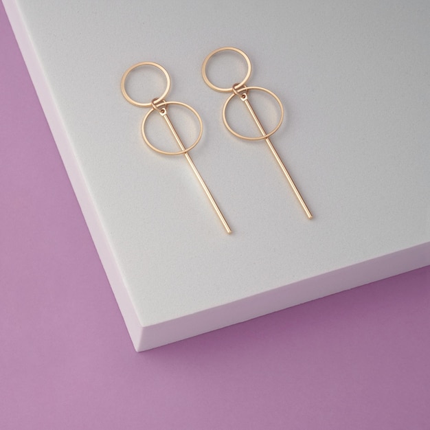 Paire de boucles d'oreilles modernes géométriques sur podium blanc avec fond violet avec espace de copie