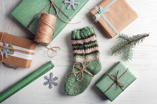 Paire de chaussettes tricotées avec des cadeaux emballés pour Noël sur table lumineuse