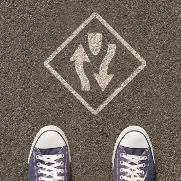 Paire de chaussures debout sur une route avec panneau de signalisation