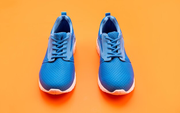Paire de chaussures de sport bleues confortables sur fond orange, sport.