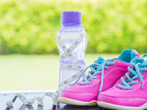 Paire de chaussures de sport roses et bouteille d&#39;eau avec fond vert bokeh