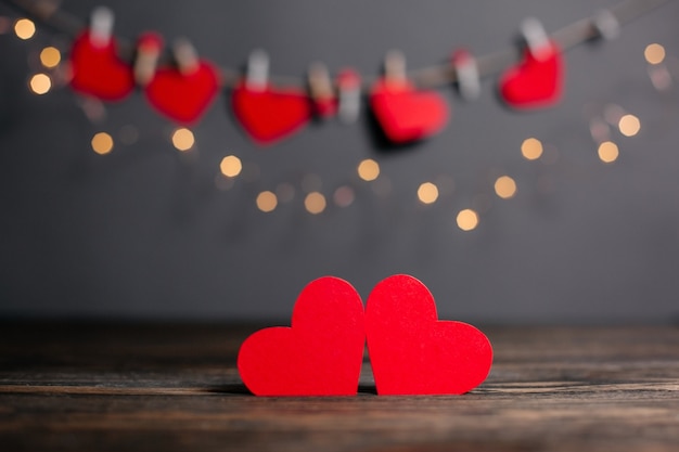 Paire de coeurs rouges sur fond de lumières, l'amour et le concept de la Saint-Valentin sur une table en bois
