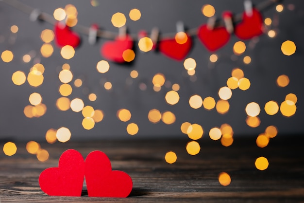 Paire de coeurs rouges sur fond de lumières, l'amour et le concept de la Saint-Valentin sur une table en bois