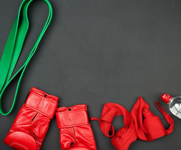 Une paire de gants de boxe en cuir rouge, un bandage en tissu et une bouteille d'eau