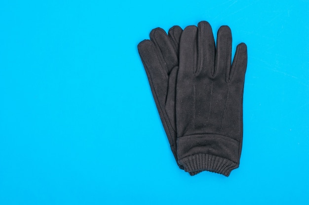 Une paire de gants en daim pour hommes sur fond bleu.