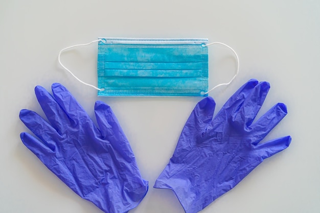 Photo une paire de gants en latex médical bleu mince et un écran facial sur fond blanc gants et masque médicaux jetables en caoutchouc sujets protecteurs remèdes