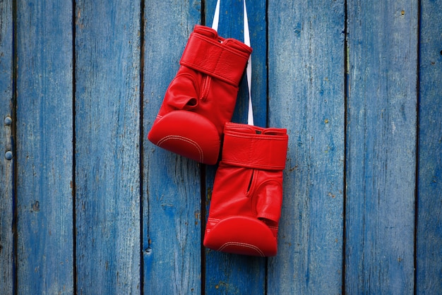 Photo paire de gants rouges pour le kickboxing suspendus à une corde blanche