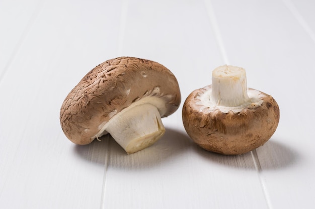 Une paire de grands champignons royaux sur une table en bois blanc. La nourriture végétarienne. Champignons cultivés artificiellement.