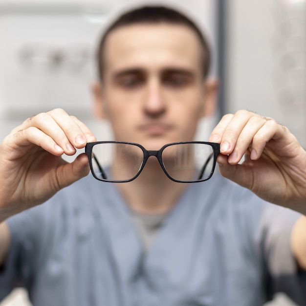 Paire de lunettes tenues par l'homme défocalisé