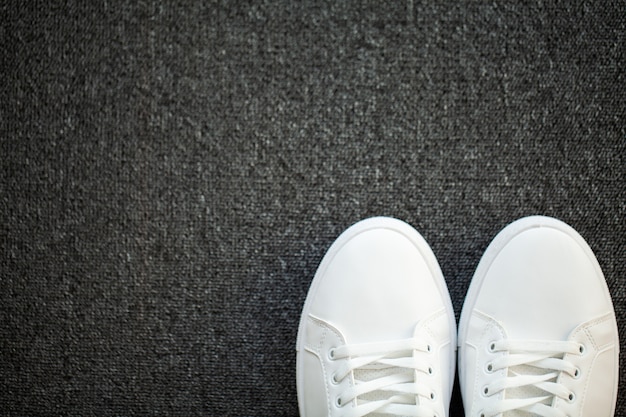 Paire de nouvelles baskets blanches élégantes au sol à la maison