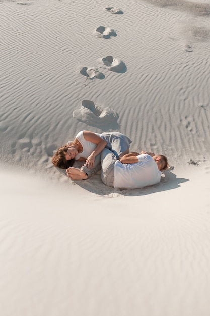 Paire romantique assis sur le sable blanc et huggins, dans le désert.