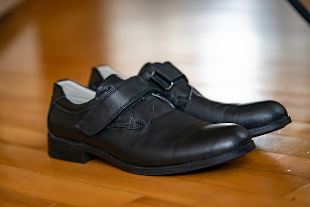 Paire de souliers noirs confortables pour hommes, isolés sur un plancher en bois.