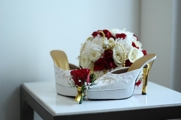 Une paire de talons hauts blancs pour femmes et un magnifique seau à fleurs roses