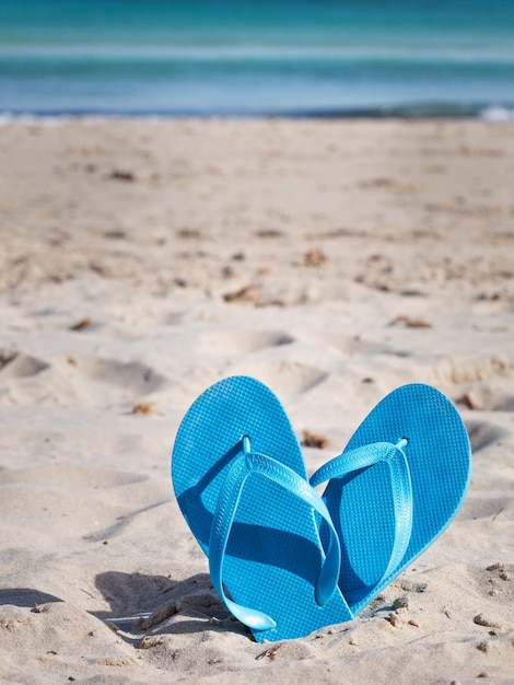 Paire de tongs bleues sur la plage de sable