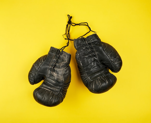 Paire de très vieux gants de boxe en cuir noir sur fond jaune