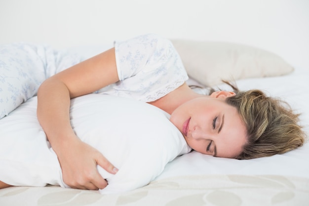 Paisible femme allongée sur le lit, embrassant l&#39;oreiller