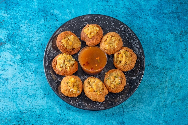 Pakistanais épicé gol gappay indien pani puri et bangali fuchka plein de chaat masala avec de l'eau aigre dans un plat isolé sur fond de marbre vue de dessus de la nourriture de rue indienne