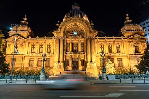 Le Palais de la CEC la nuit et une longue exposition, éclairage jaune, trace de voiture en mouvement au premier plan à Bucarest, Roumanie