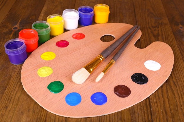 Palette d'art en bois avec de la peinture et des pinceaux sur la table libre