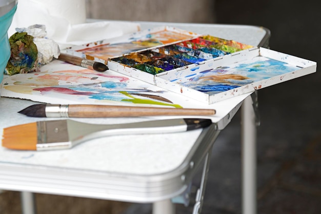 Photo palette d'art avec des peintures à l'huile et des pinceaux sur une table