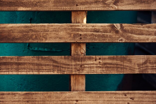 Une palette en bois est appuyée contre une structure en fer vert.
