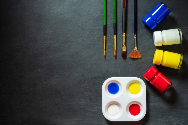 Palette et bouteilles de couleur avec pinceaux sur table en ciment