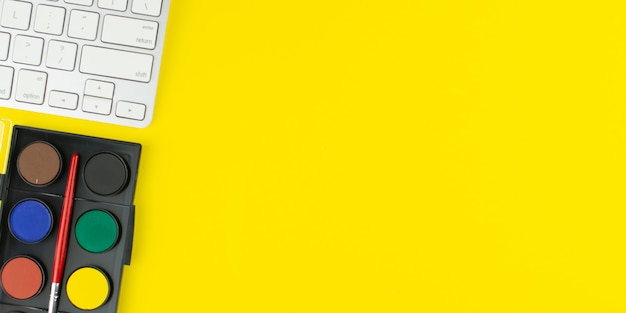Palette de couleurs de peintre et clavier sur fond jaune.