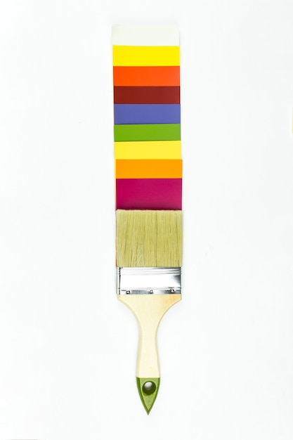 Palette de couleurs et pinceau avec manche en bois sur fond blanc.
