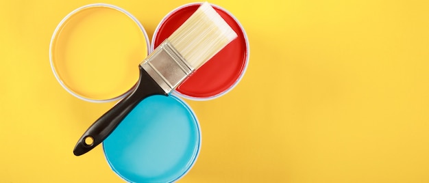 Palette de couleurs de pots de peinture avec pinceau sur fond jaune, concept de rénovation domiciliaire