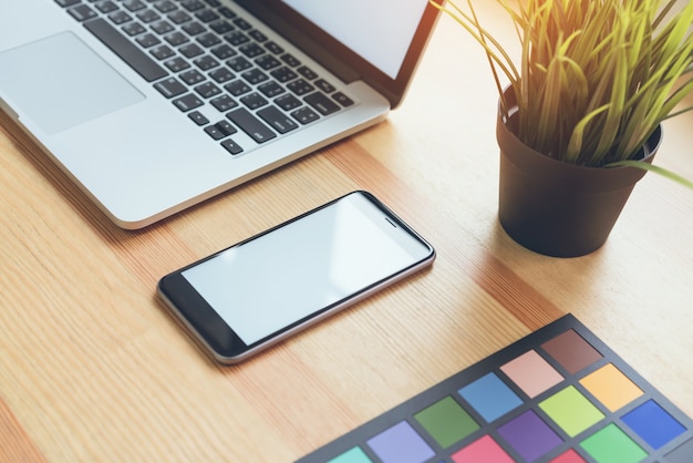 Palette de maquillage, smartphone et ordinateur portable sur table en bois