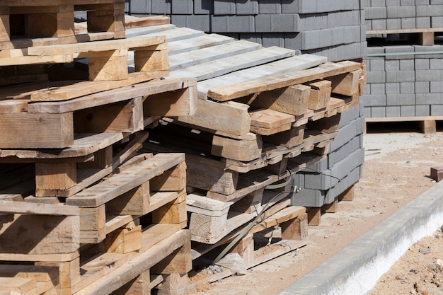 Palettes en bois vides et nouvelles tuiles de construction pour la pose de chemins et de routes