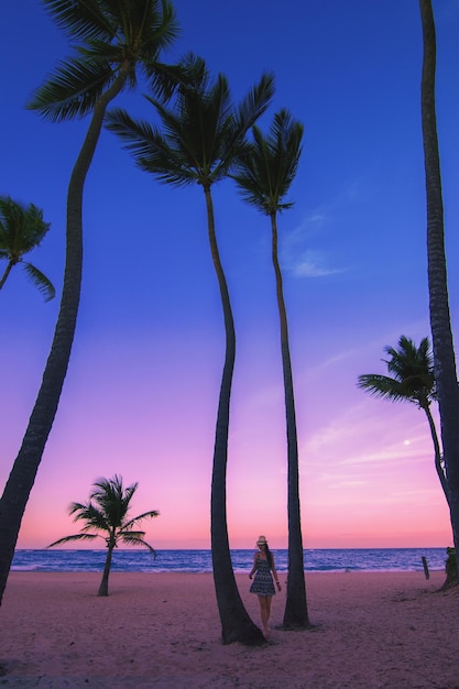Photo des palmiers et une femme sur la plage contre le ciel