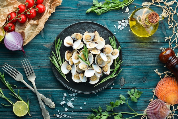 Palourdes bouillies aux épices dans une assiette. Fruits de mer sur fond noir. Vue de dessus. Espace de copie gratuit.