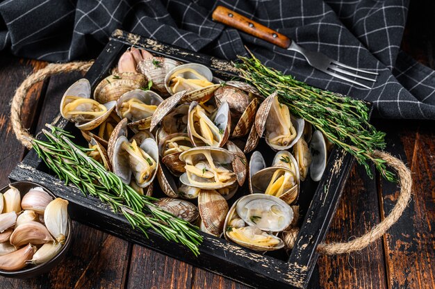 Palourdes vongole dans un plateau en bois avec des herbes