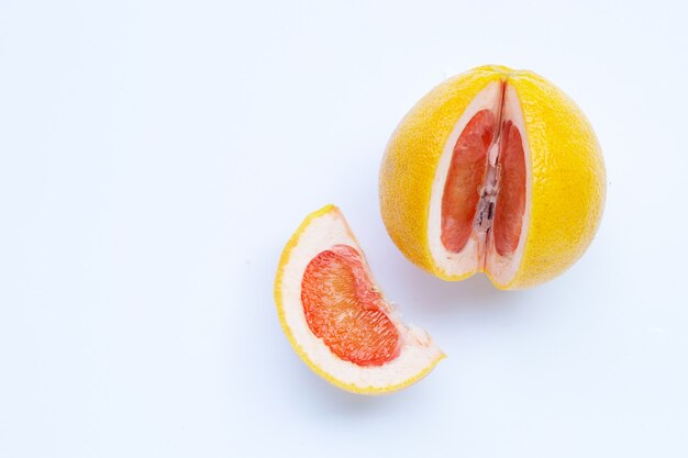 Pamplemousse juteux riche en vitamine C sur un mur blanc.