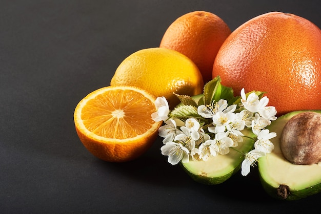 Pamplemousse, orange et avocat, isolés sur fond noir.