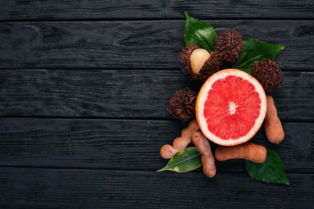 Pamplemousse ramboutan et tamarin Fruits tropicaux frais Sur un fond en bois Vue de dessus Copier l'espace