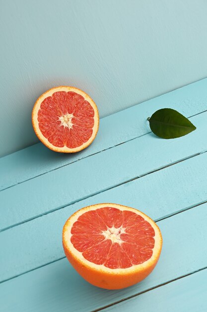 Pamplemousse rouge coupé en deux sur un fond rustique en bois bleu.