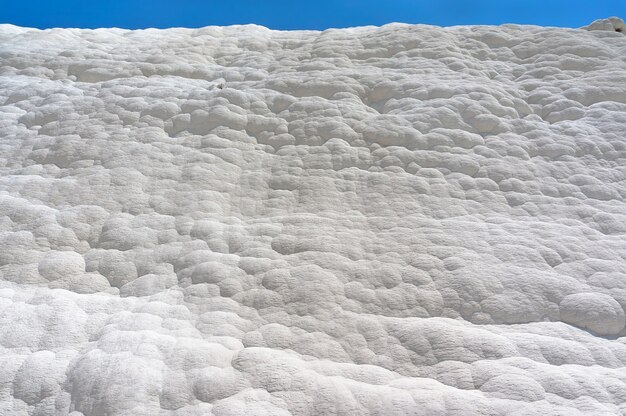 Pamukkale, Château De Coton, Merveille Naturelle Est Créée Par Des Couches De Travertin Blanc Ressemblant à Du Coton, Turquie. Mur Naturel De Pamukkale Contre Un Ciel Bleu