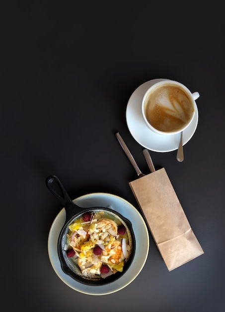 Pan avec cheesecake ou crêpes et baies, tasse de café sur la table sombre, vue de dessus.