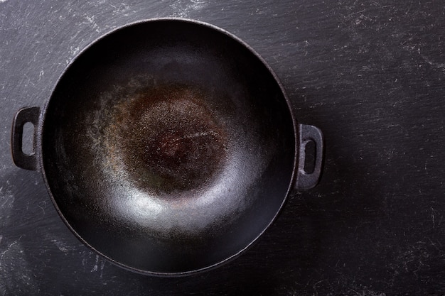 Pan wok vide sur une table sombre, vue du dessus