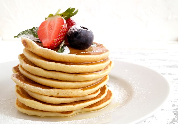 Pancakes américains avec des baies sur un fond clair.