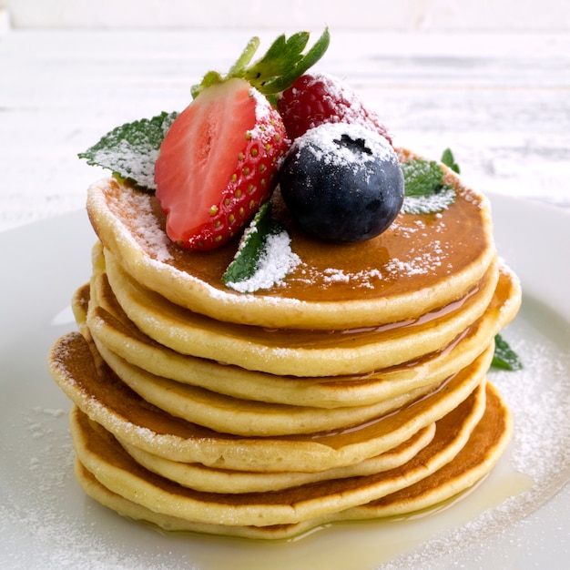 Pancakes américains avec des baies sur un fond clair.