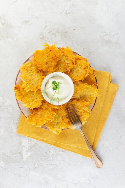 Pancakes de pommes de terre draniki Latkes ou Levivot avec de la crème aigre et des petits pois verts dans une assiette